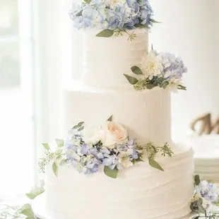a white wedding cake with blue flowers
