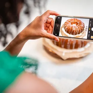 a woman taking a picture of a cake