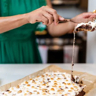a woman spreading marshmallows on a cake