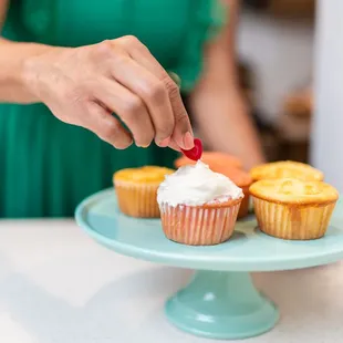 a woman decorating cupcakes