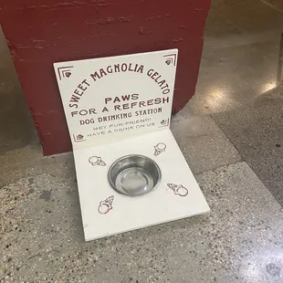 a dog&apos;s water bowl in front of a sign