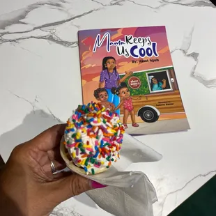 a person holding a doughnut with sprinkles