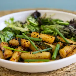 Korean savory rice cake with soy sauce served with fresh veggie salad.