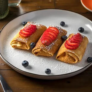 a plate of crepes with strawberries and blueberries