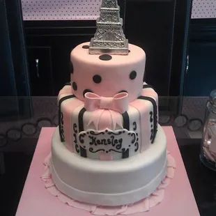 a three tiered cake with the eiffel tower in the background