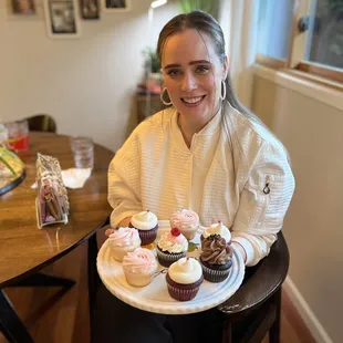 a woman holding a plate of cupcakes