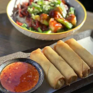 a bowl of dipping sauce and a plate of spring rolls