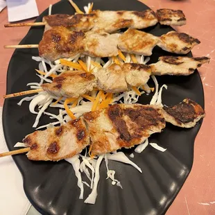 skewered chicken on a black plate
