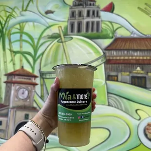 a hand holding a cup of juice