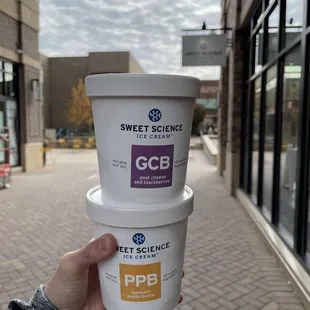 a person holding two cups of ice cream