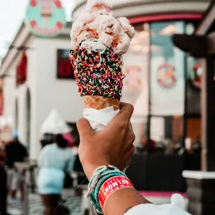 a person holding up an ice cream cone with sprinkles