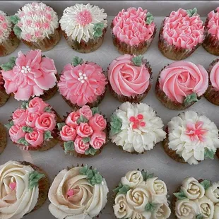 a tray of cupcakes with pink and white frosting