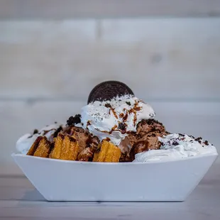 Oreo Churro Delight: Warm Churro Bites topped with Ice Cream, Sprinkles, Chocolate Syrup, Oreo Crumbs and Whip Cream.