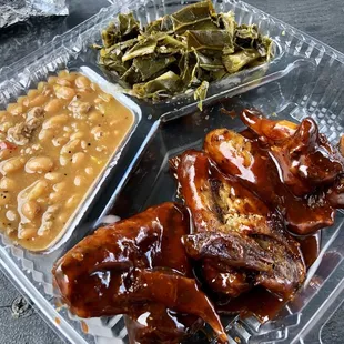 a plate of ribs, beans, and greens