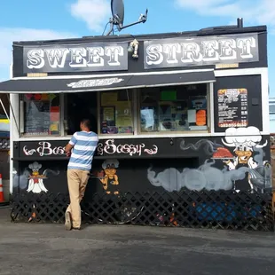 a man standing in front of a sweet street bbq