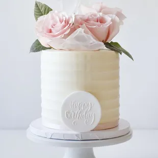 a white cake with pink roses on top