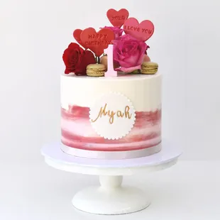 a pink and white cake with red roses