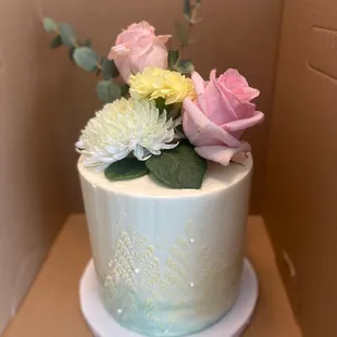 Custom chocolate cake with white butter cream and flower topper.