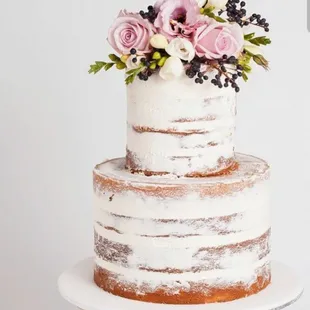 a three tiered cake with fresh flowers on top