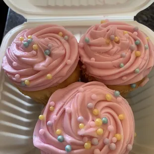 Delicious butter cupcakes with pink vanilla butter cream frosting with candy pearls
