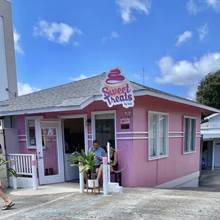 a woman sitting outside a pink shop