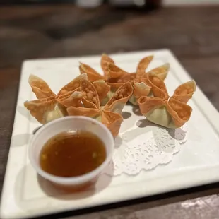 a plate of wontons with dipping sauce
