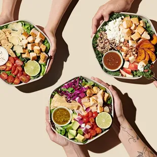 hands holding bowls of food