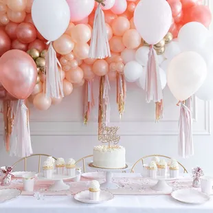 a table with a cake and balloons