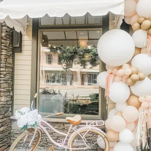 a bicycle and balloons in front of a store