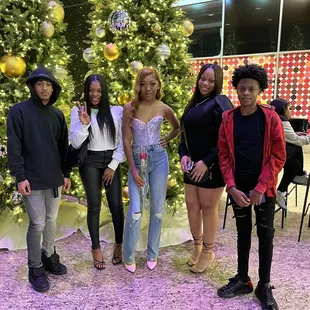 a group of people standing in front of a christmas tree