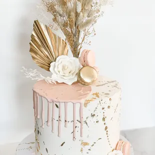 a white and pink cake with gold drips