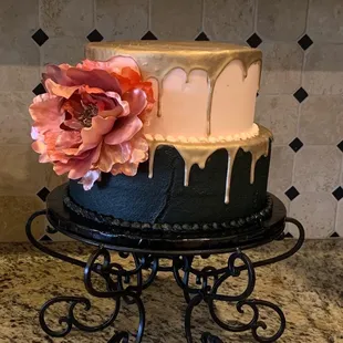 a black and white cake with a pink flower on top