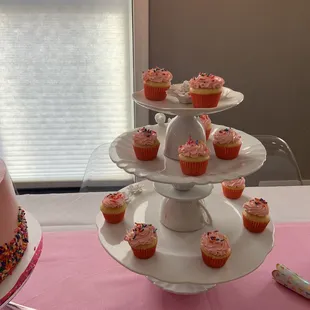 a three tiered cake and cupcakes