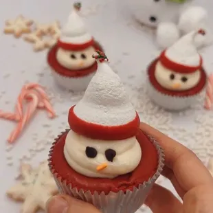 a hand holding a cupcake with frosting and decorations