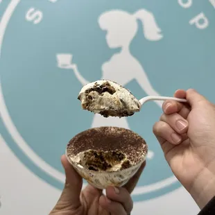 a hand holding a spoon full of ice cream