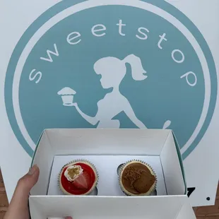 a person holding a box of cupcakes