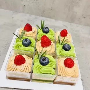 a tray of cupcakes with green frosting and berries