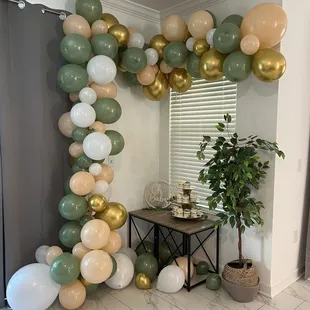 a balloon arch made of gold, green and white balloons