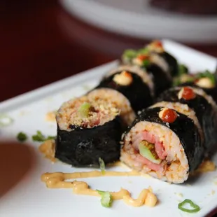 a plate of sushi rolls and a bowl of sauce