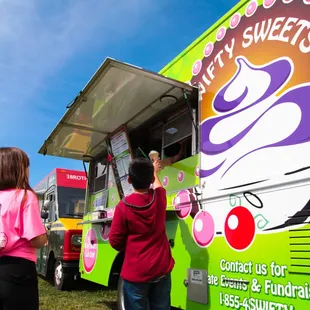 two people standing in front of a food truck