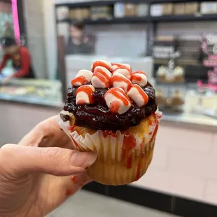 a hand holding a cupcake