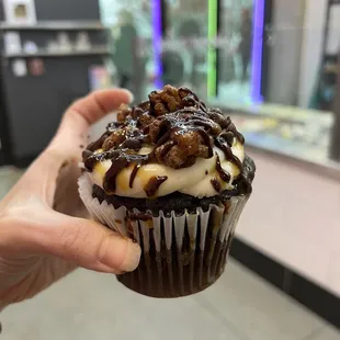 a hand holding a cupcake