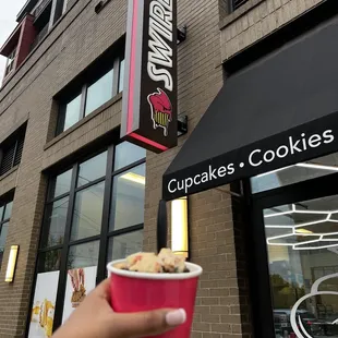 a hand holding a cup of ice cream