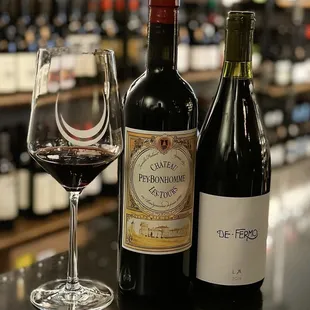 three bottles of wine and a glass of wine