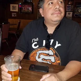a man sitting at a table with a glass of beer