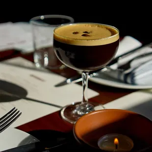 a glass of coffee and a candle on a table