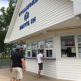 two men standing outside of a store
