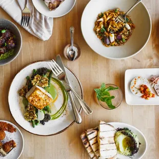 a wooden table with plates of food and utensils