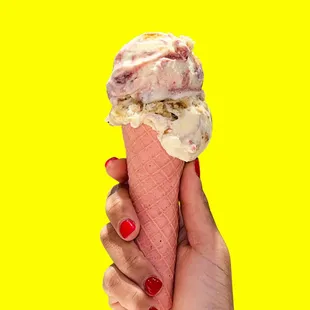 a hand holding a cone of ice cream