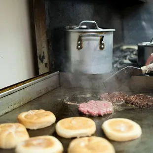 a person cooking hamburgers on a grill
